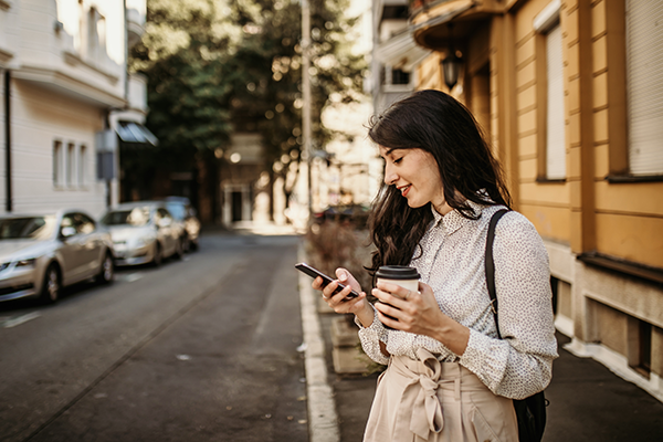 Woman checking her phone on the side of a street